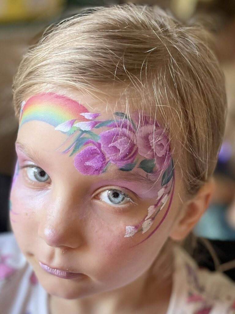 childrens face painting rainbow and flowers design at a party in london
