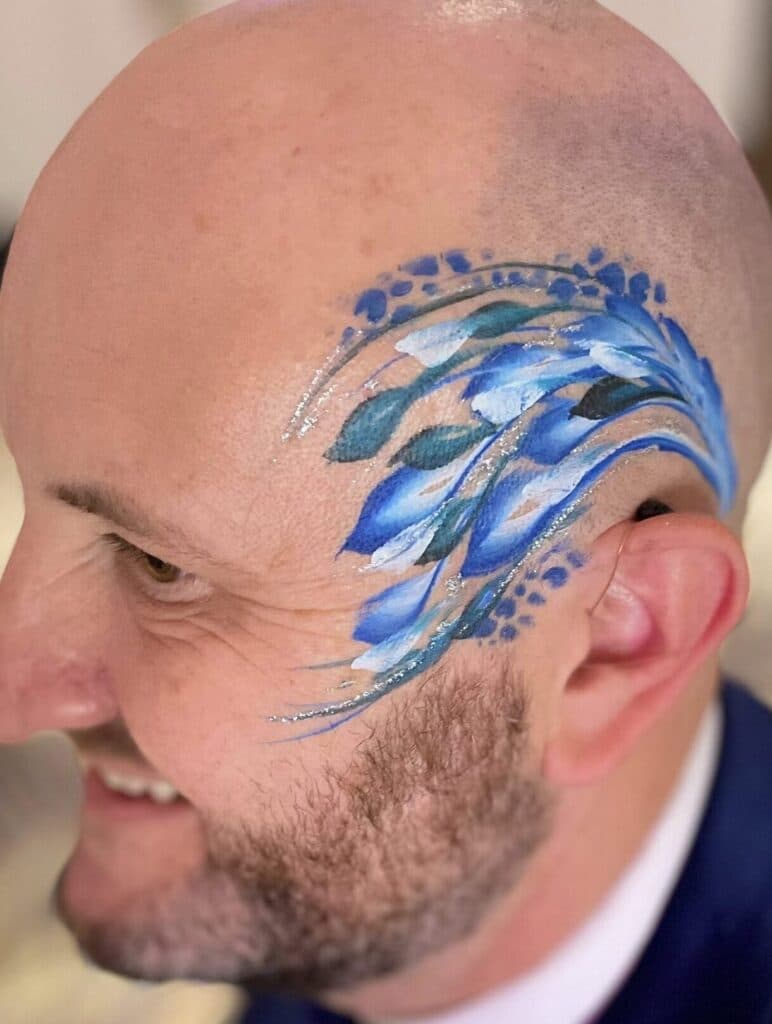 A man with a blue and green leaf face paint at a London corporat event